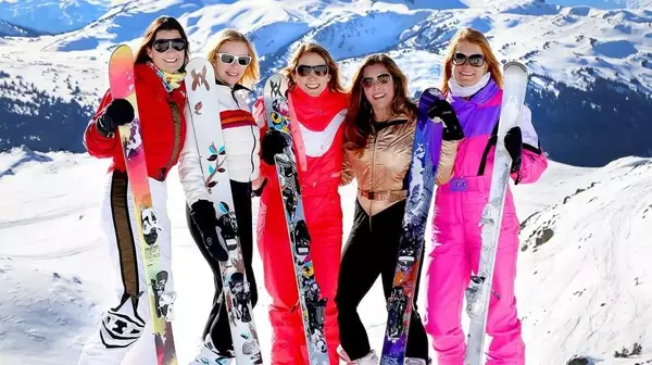 Women in snowsuits in the mountains with skis
