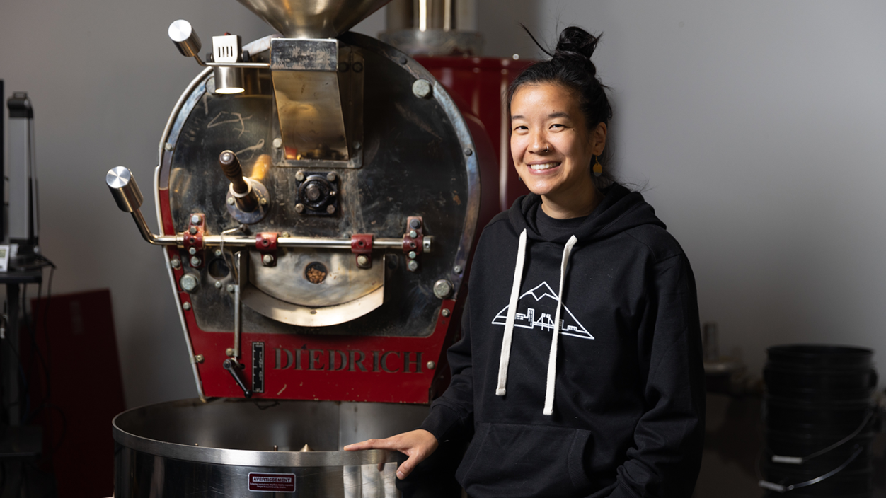 Benita Ki ’11 in front of a coffee roasting machine.