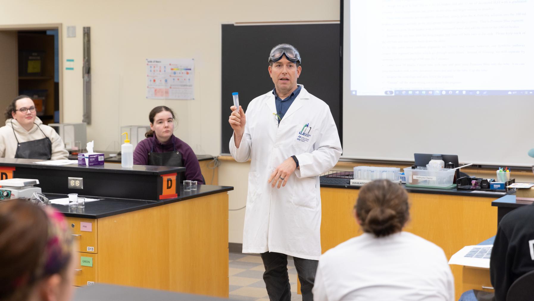 Prof. Dan Burgard, wearing a lab coat and safety goggles, gives a safety talk in class.