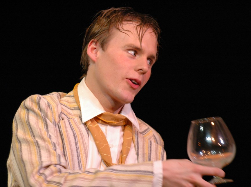 Actor holding a wine goblet in dialogue