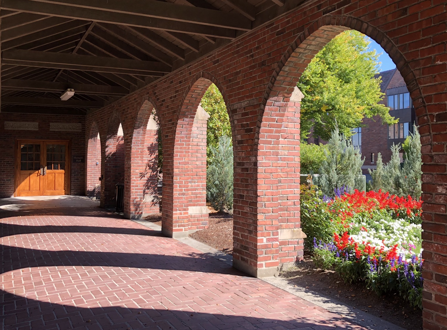 Walkway to Howarth Hall under arches and with flowers