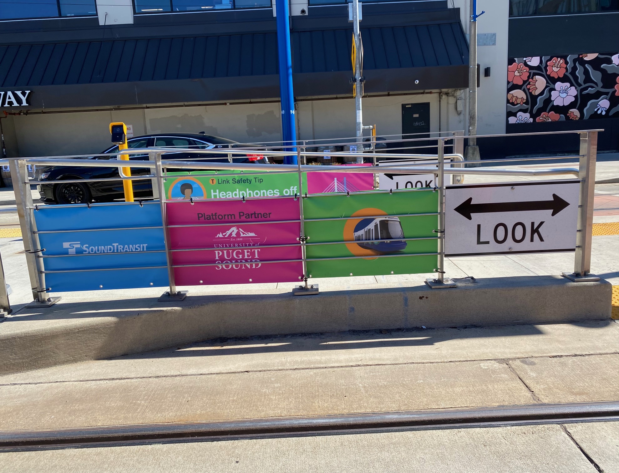 Signs are displayed on a fence with Sound Transit and the University of Puget Sound logos visible. 