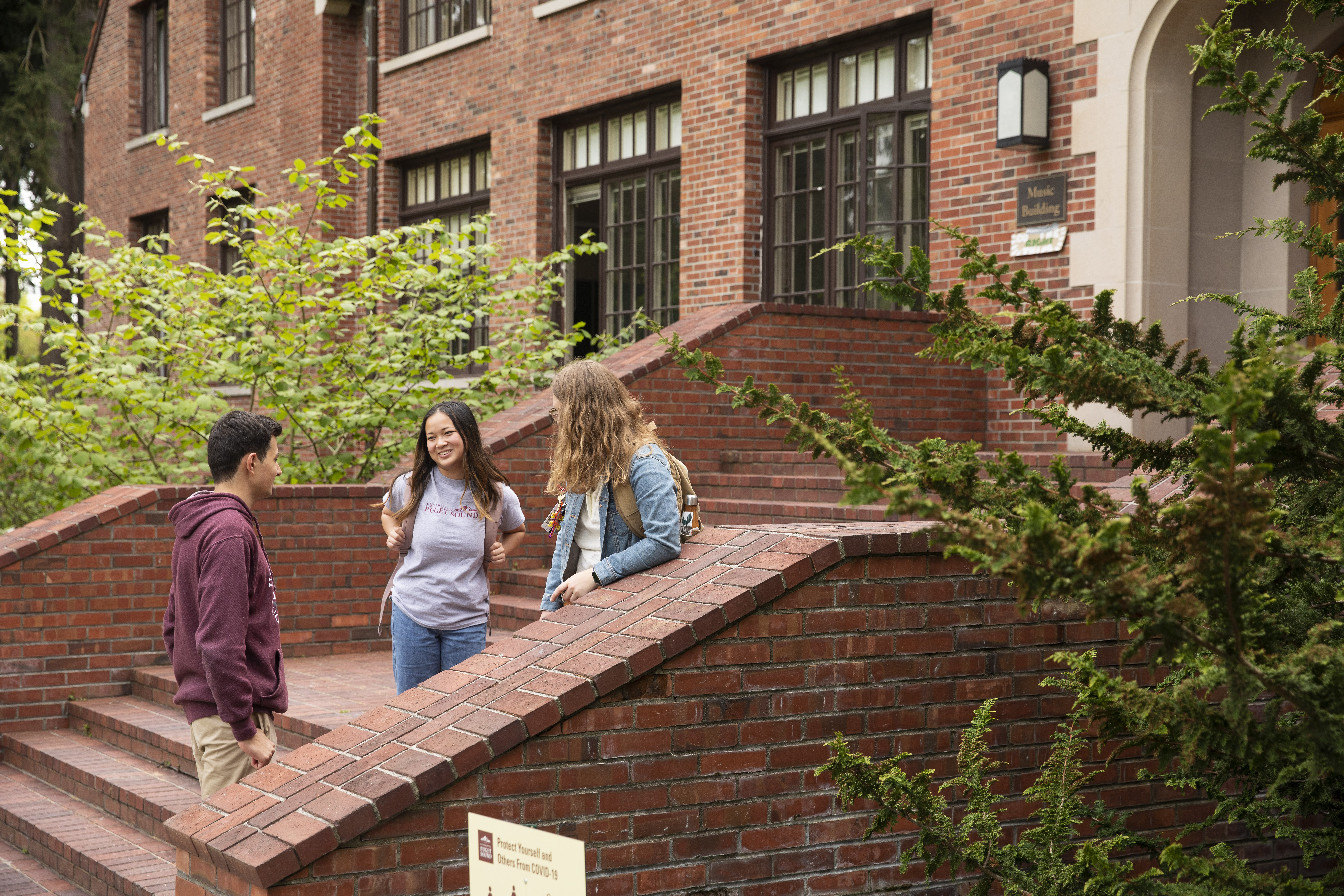 Students chat on the brick steps of one of the campus buildings.