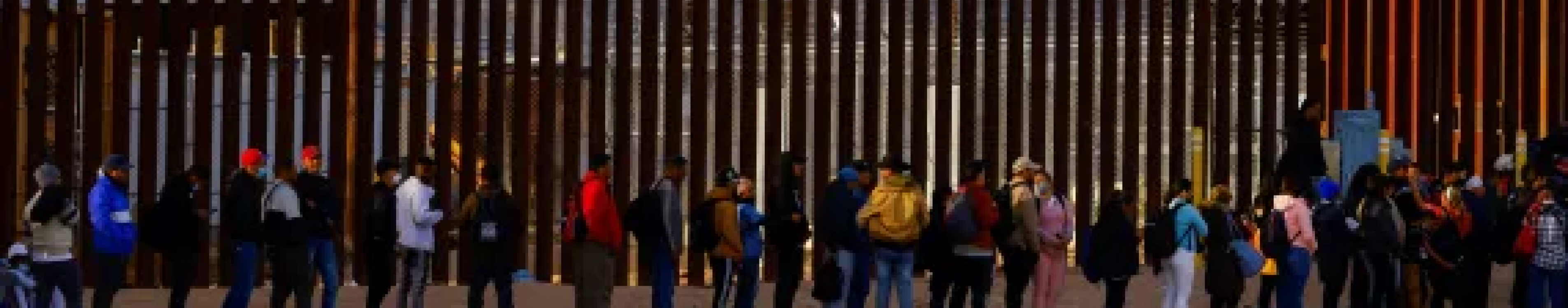 A group of people in front of the Mexico-America boarder