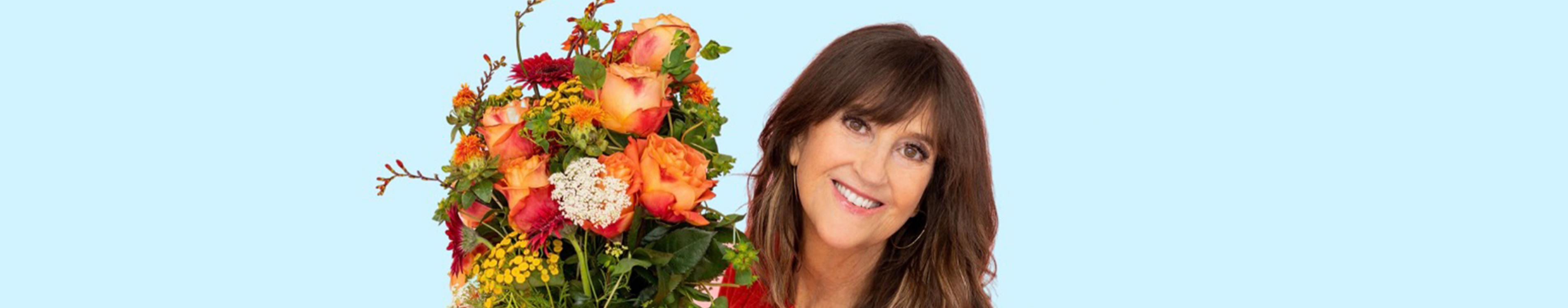 Author Jennifer Cramer-Miller looks at the camera and smiles while holding a bouquet of flowers.