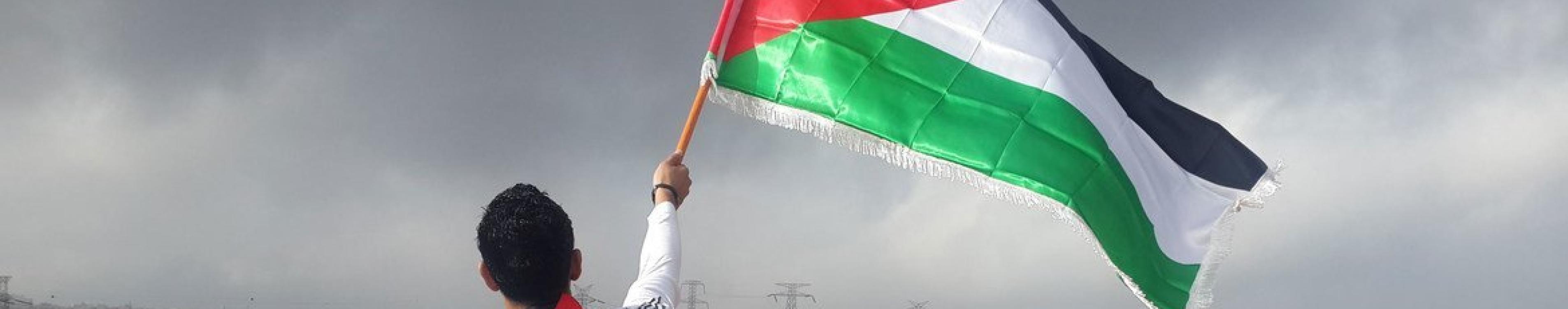 Unsplash/Ahmed Abu Hameeda Young man waves flag of Palestine