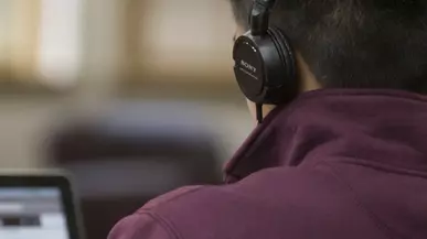 Person wearing headphones looking at a laptop