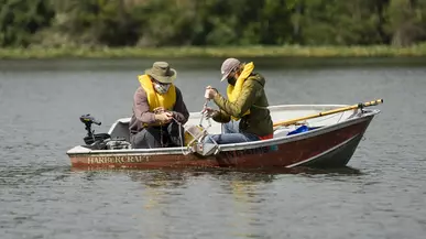 Two people using equipment in a boat on a lake