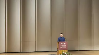 Viet Thanh Nguyen stands at a podium onstage at Schneebeck Concert Hall