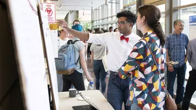 Male student shares research poster with female guest