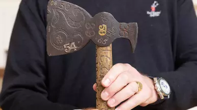 An alumnus from the Class of 1973 holds the original hatchet at Summer Reunion Weekend 2023.