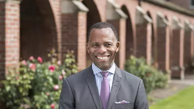 President Isiaah Crawford smiles at the camera while standing outside the arches on campus. 