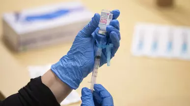 A hand is seen pulling medicine into a syringe