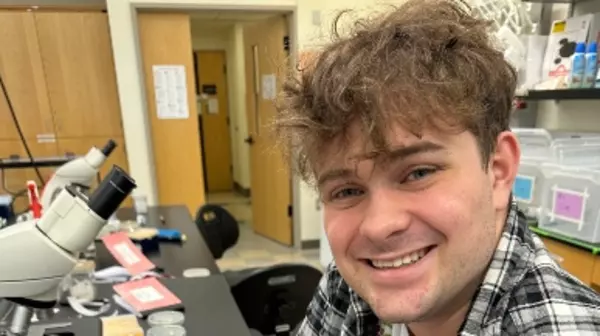 Preston in a lab with microscopes in the background