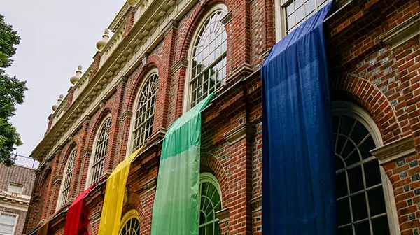 Colorful flags draped over brick building facade