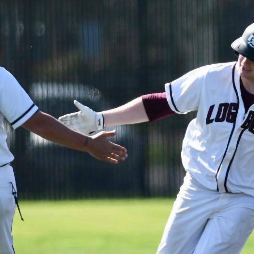 Logger baseball players tap hands as one rounds the bases.