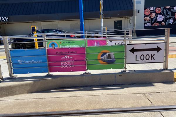 Signs are displayed on a fence with Sound Transit and the University of Puget Sound logos visible. 