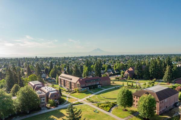 Image taken over campus with buildings below, trees stretched out to the horizon, and Mount Rainier in the distance.