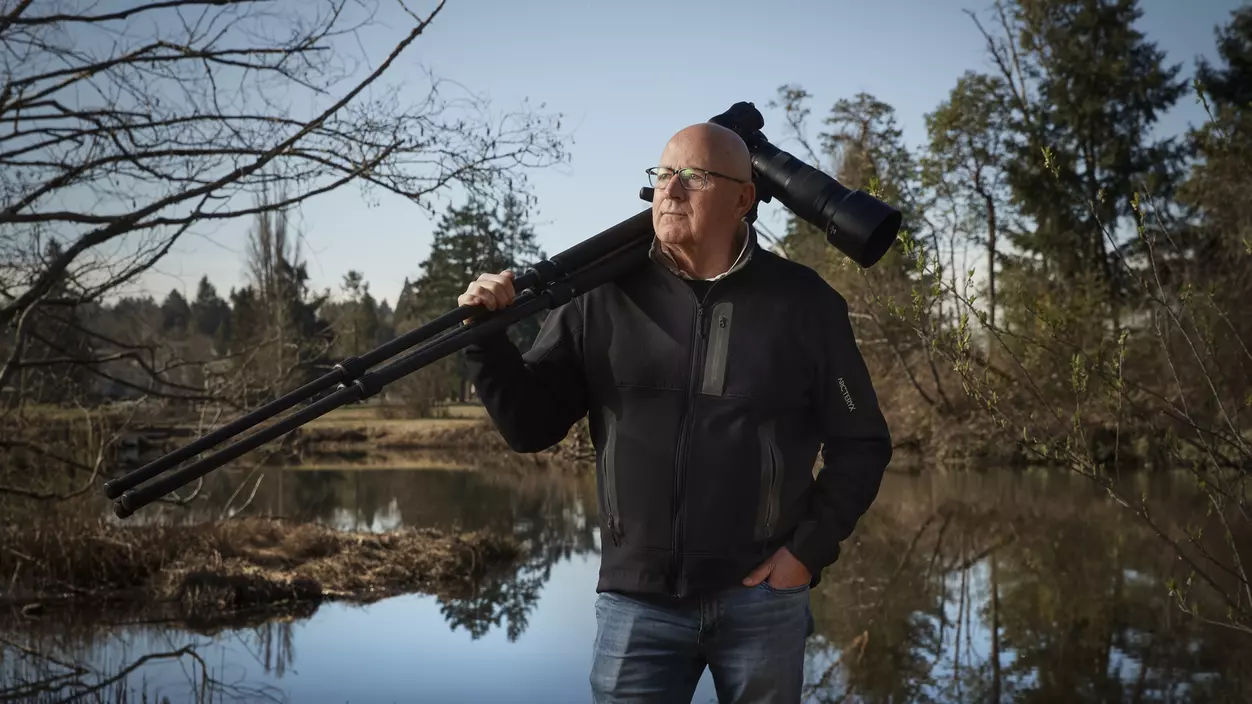 Dan Clements '71, P'07, holding a camera in a wildlife area