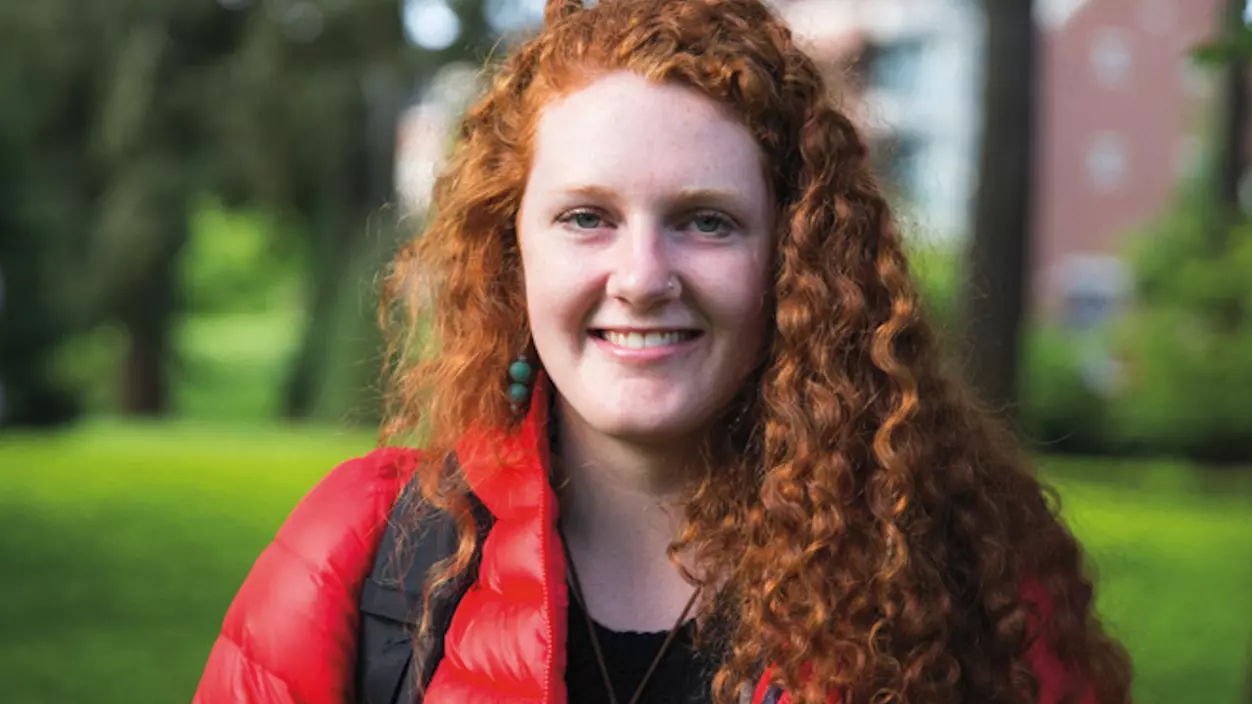 Clara Brown '17 standing on campus wearing a red coat