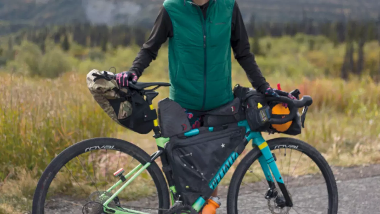 Person standing with a bike standing in a scenic outdoor area