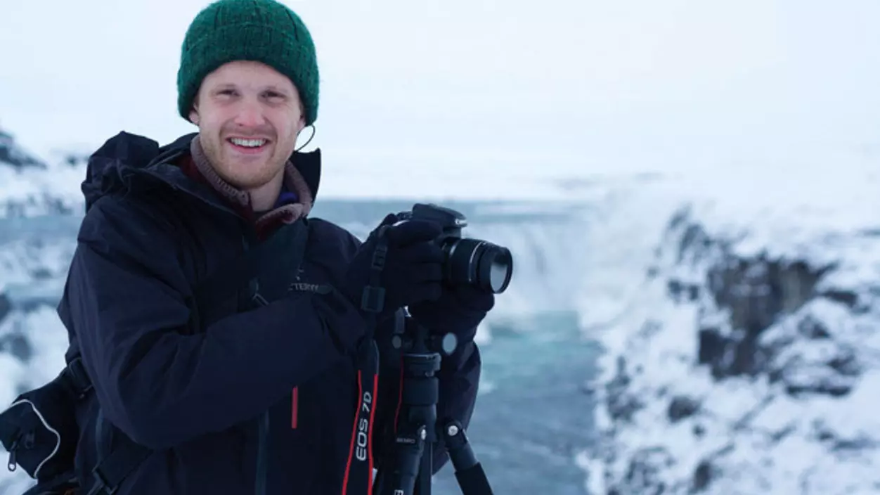 A person outdoors in the snow with a camera on a tripod