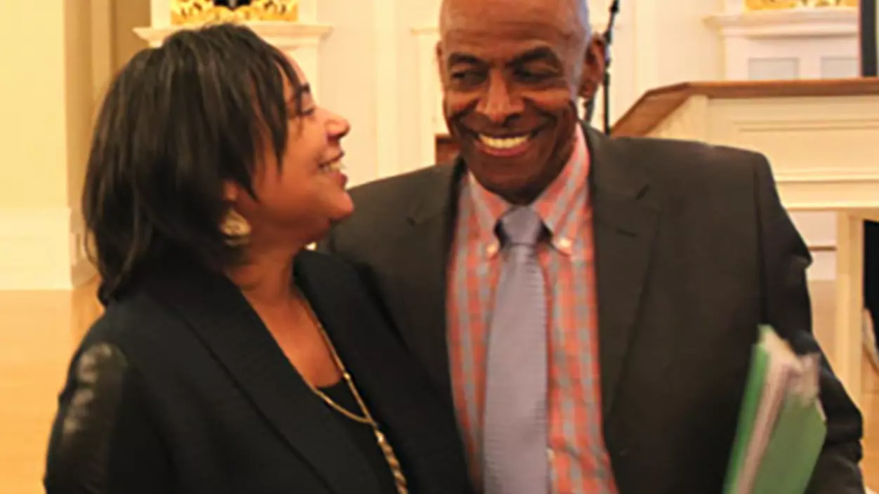 Two people smiling in front of a pipe organ