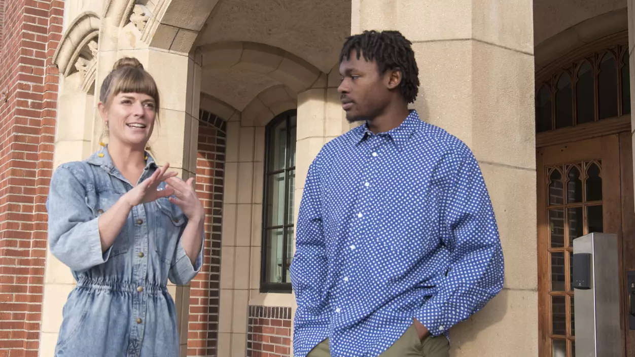 Two people talking in front of the entrance of a school