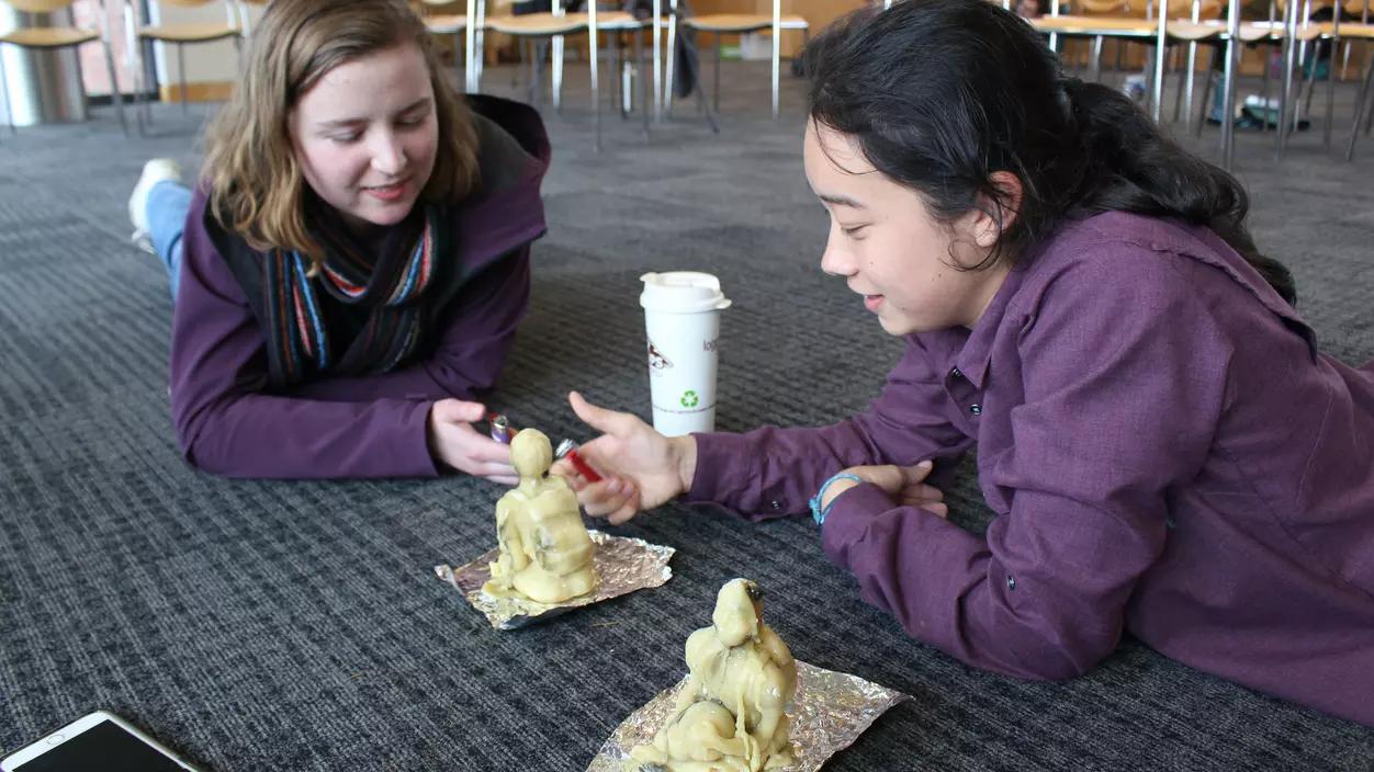 Two people sitting on the floor creating sculptures