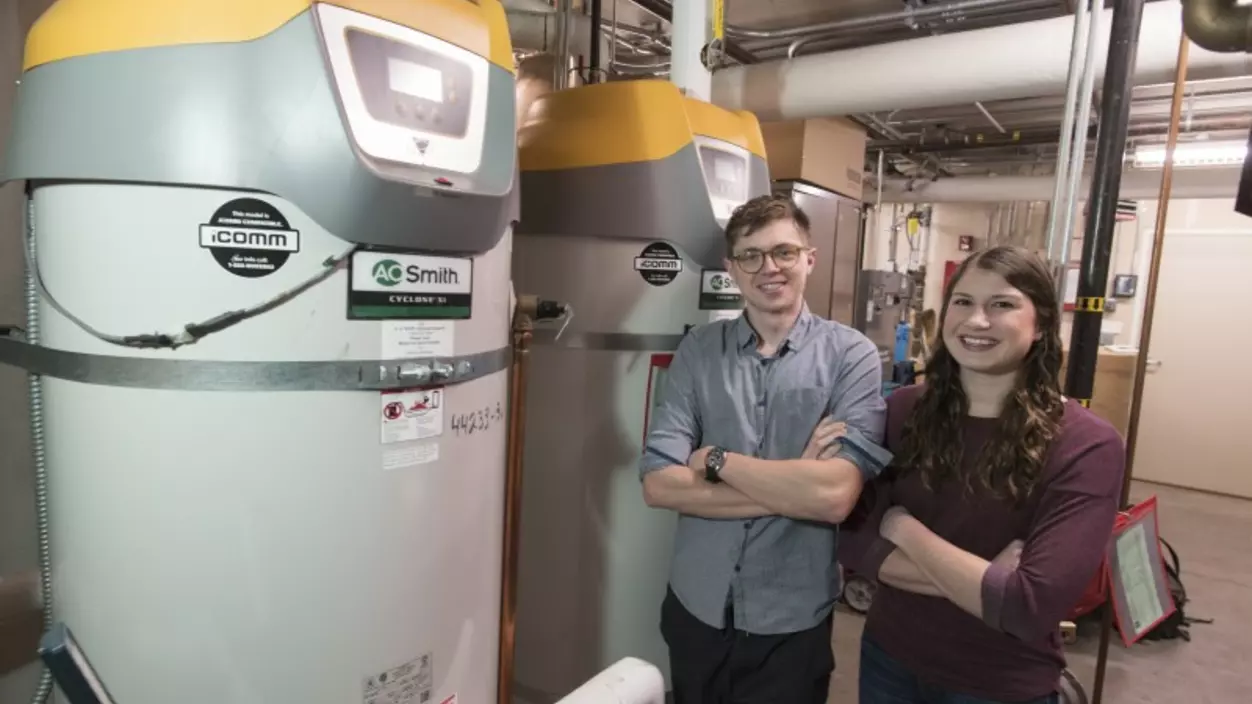 Two people standing in front of water heaters