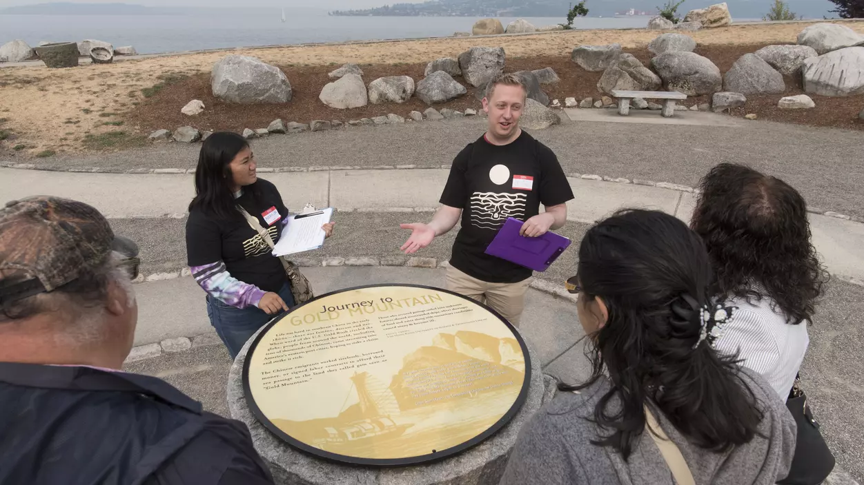 A group of people standing around an informational plaque and talking