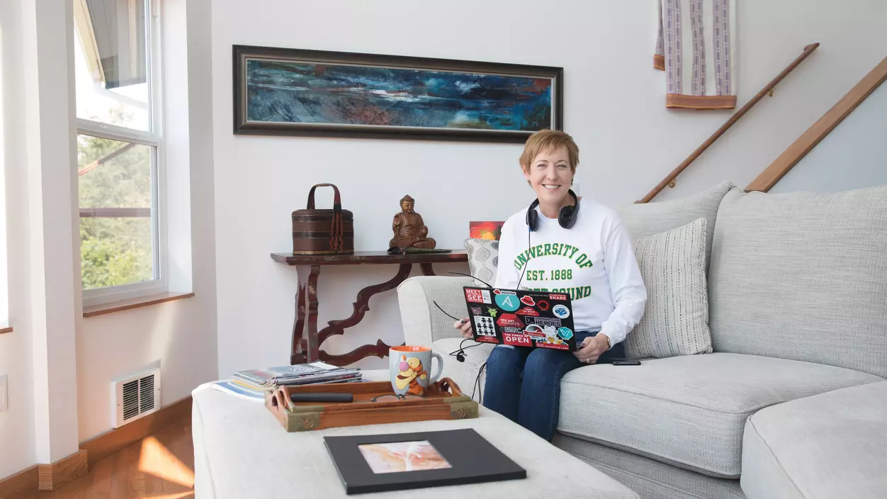 A person in a living room using a laptop and headphones