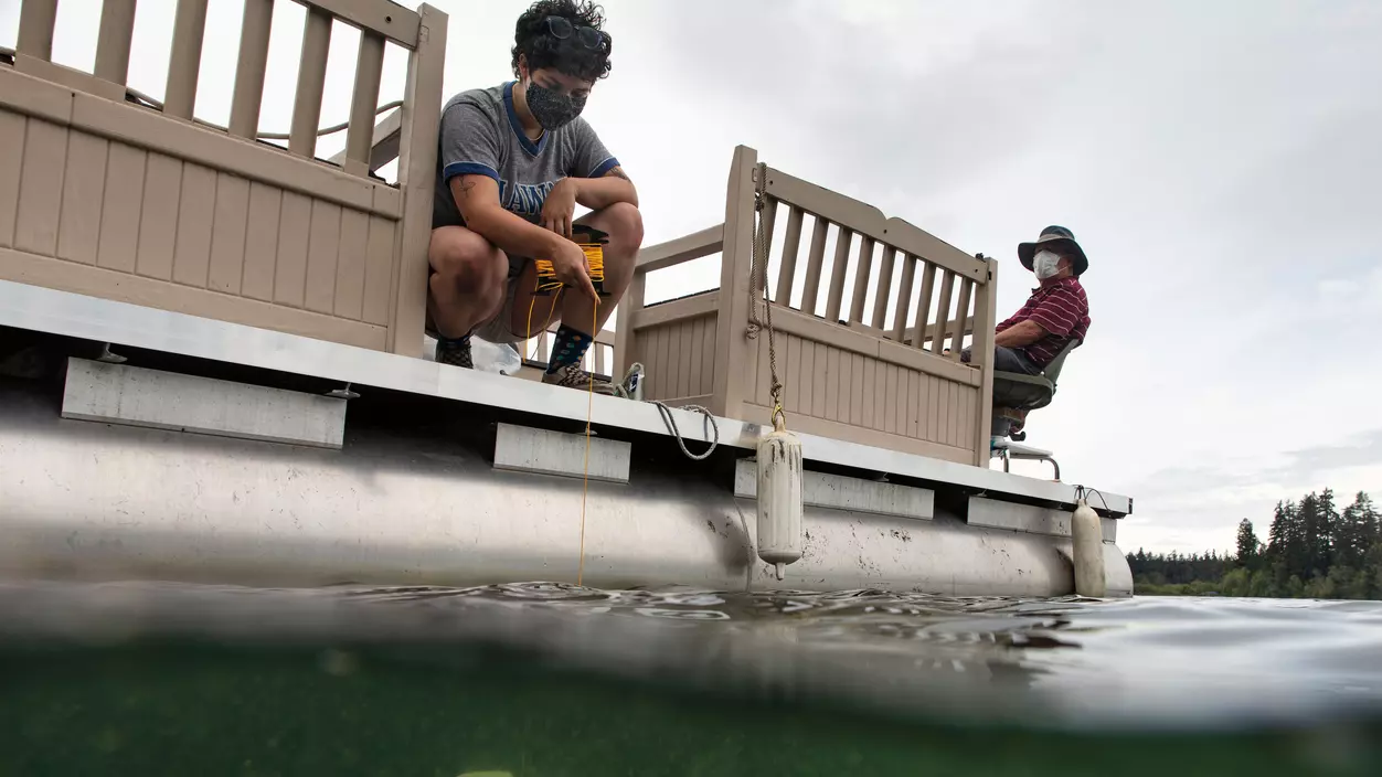 Two people on the dock of a lake