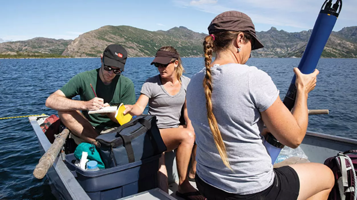 Three people on a boat holding testing equipment