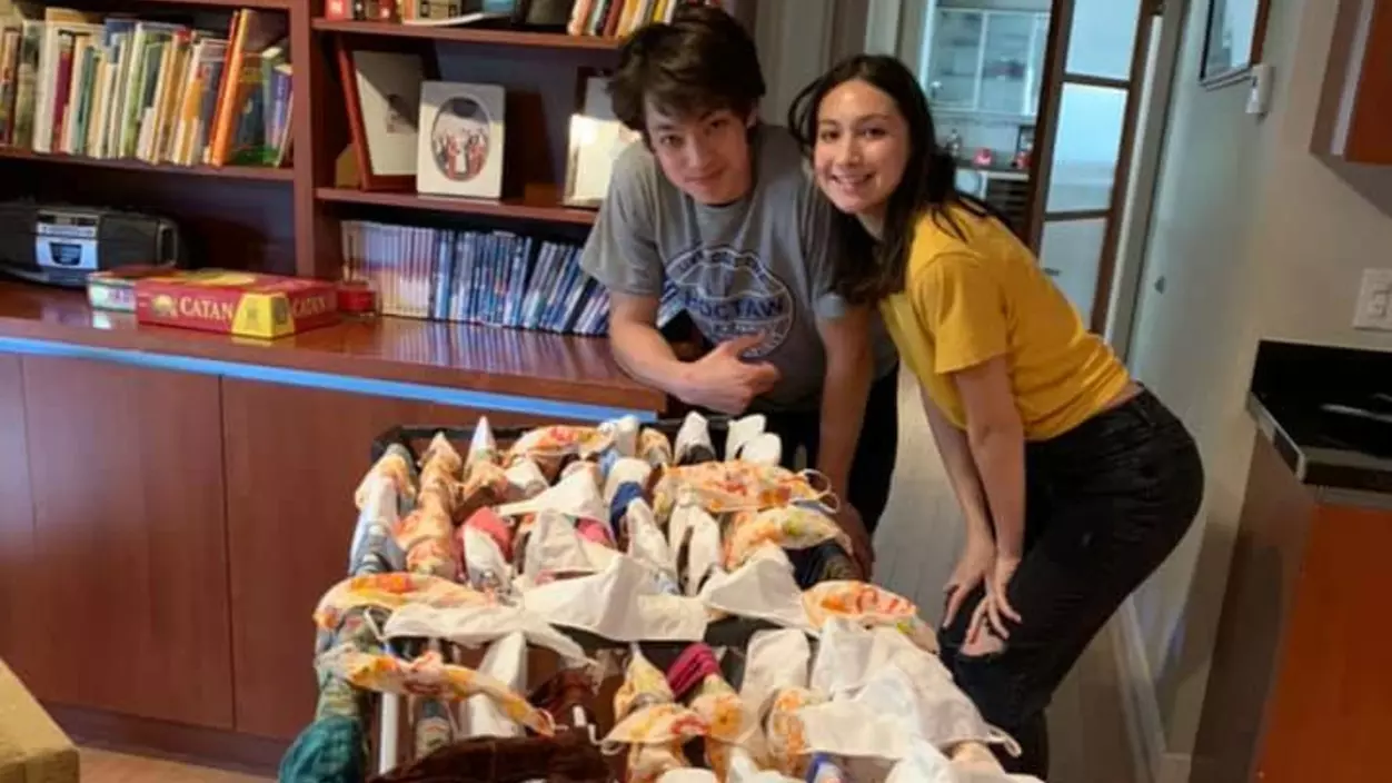 Two people posing with a collection of fabric masks