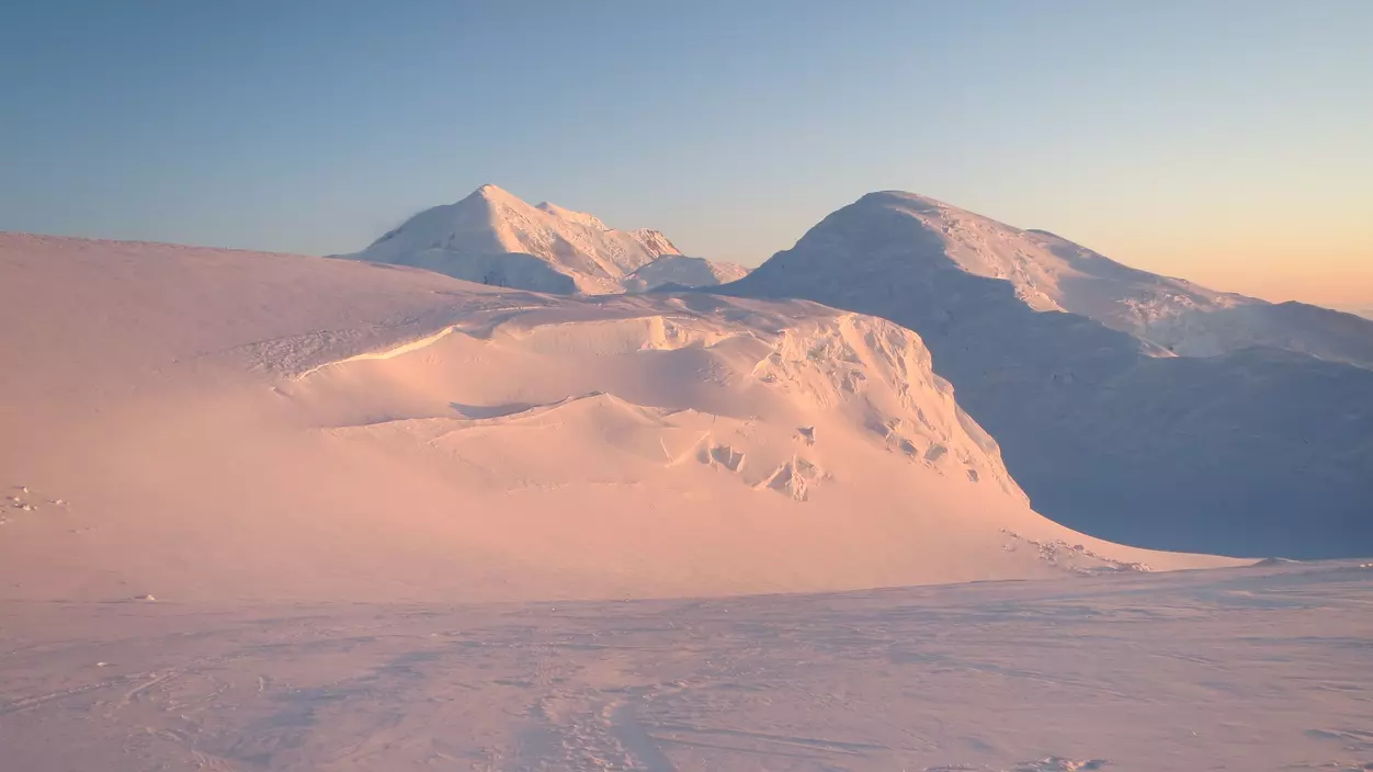 Snowy mountain as seen in the glow of the rising sun.