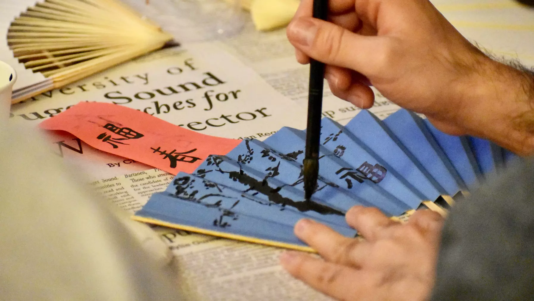 Student painting a fan at Chinese New Year celebration