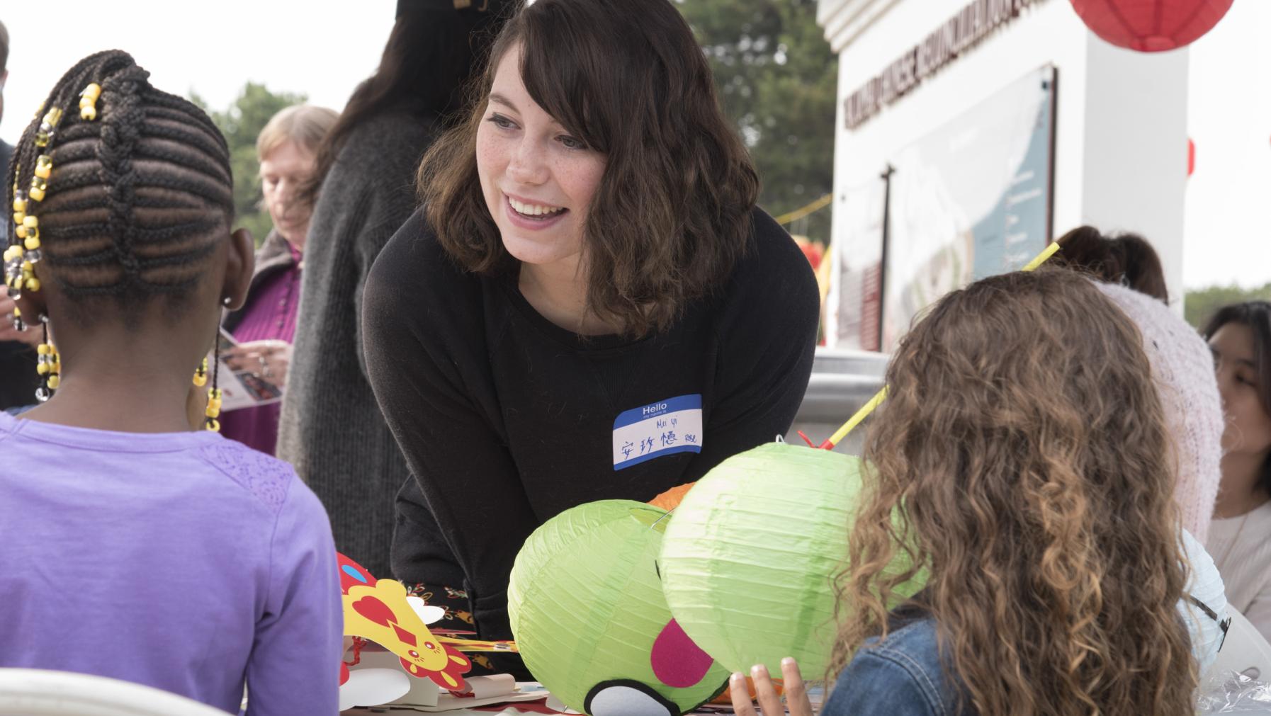 A person holding green decorations and talking to children