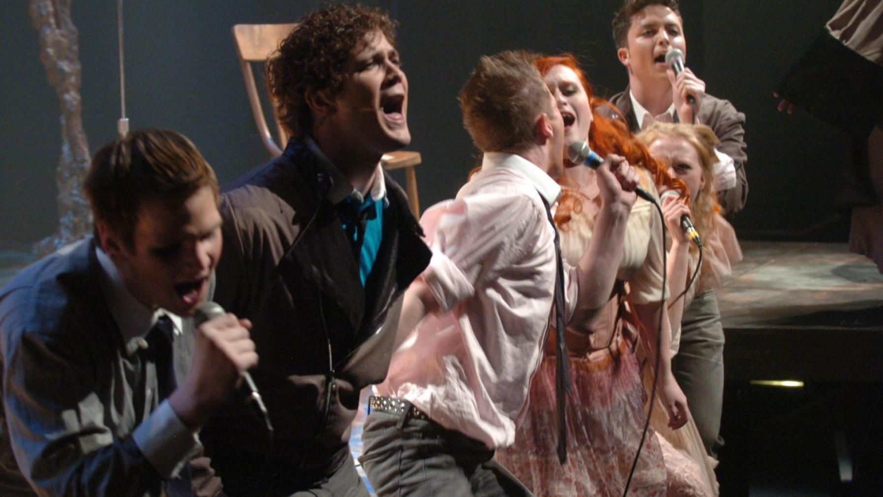 A cast singing on stage