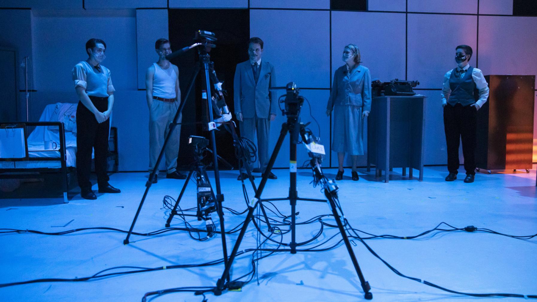 A group of students onstage in Norton Clapp Theatre during a performance of Machinal, streaming cameras visible in the foreground