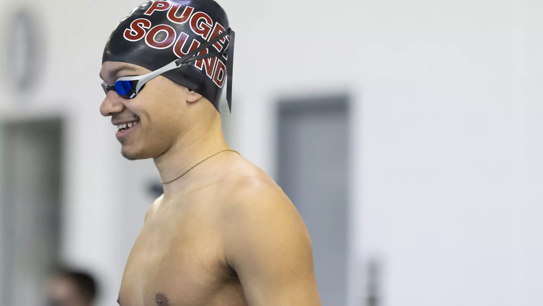 Jaden Francis ’25, in swimming cap and goggles, smiles as he prepares to dive into Wallace Pool