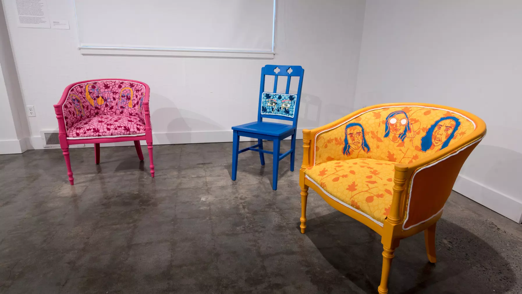 A display of three colorful chairs with artworks painted on them