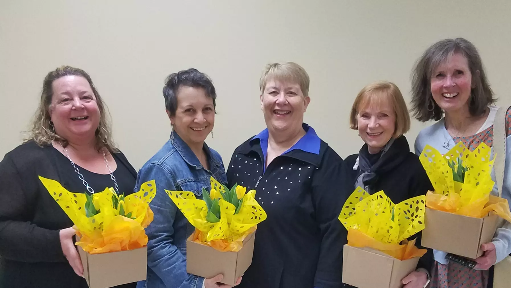 5 smiling members of the Women's League hold boquets of flowers