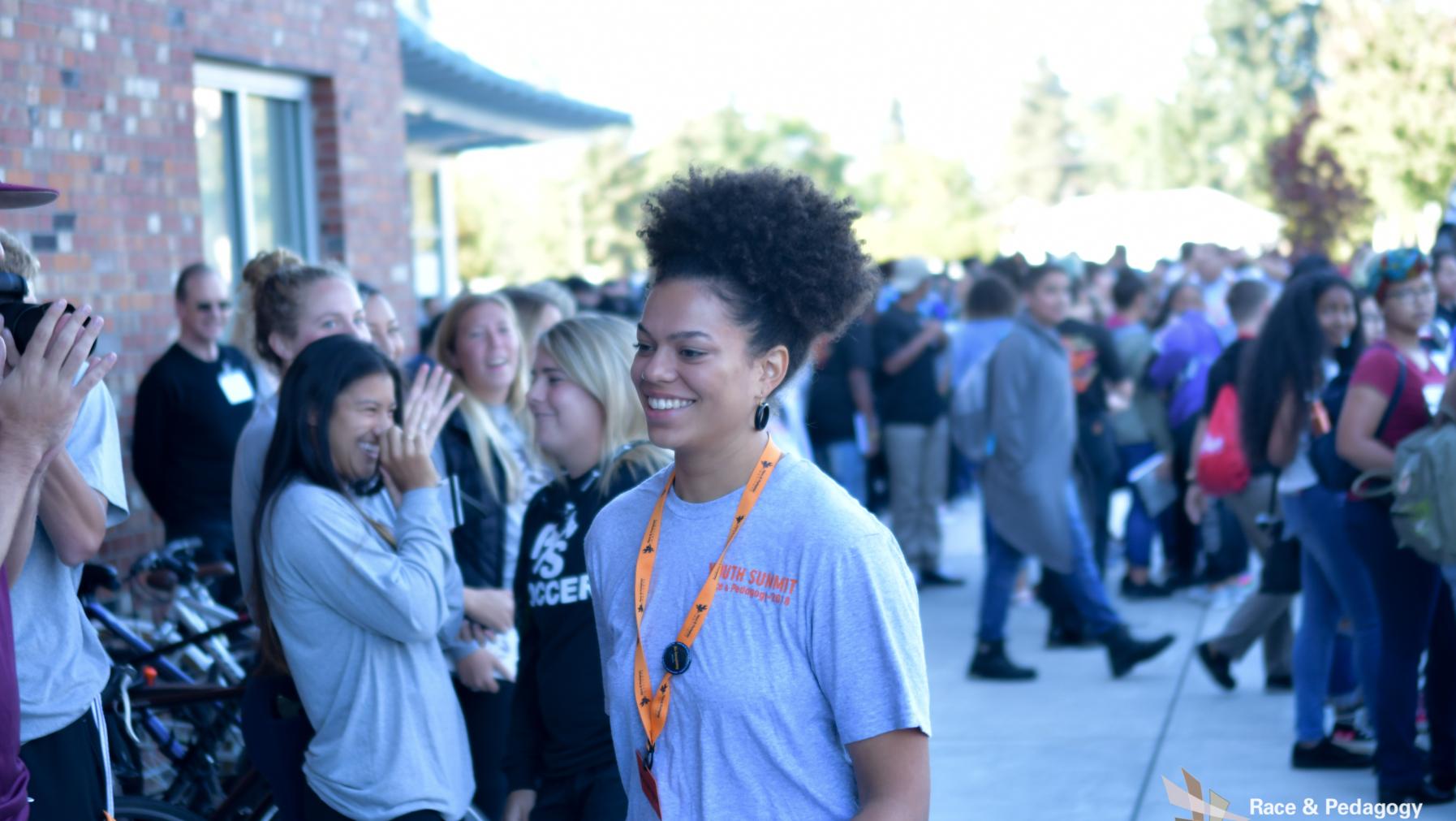 Puget Sound Student leader entering the fieldhouse amongst youth summit participants, smiling