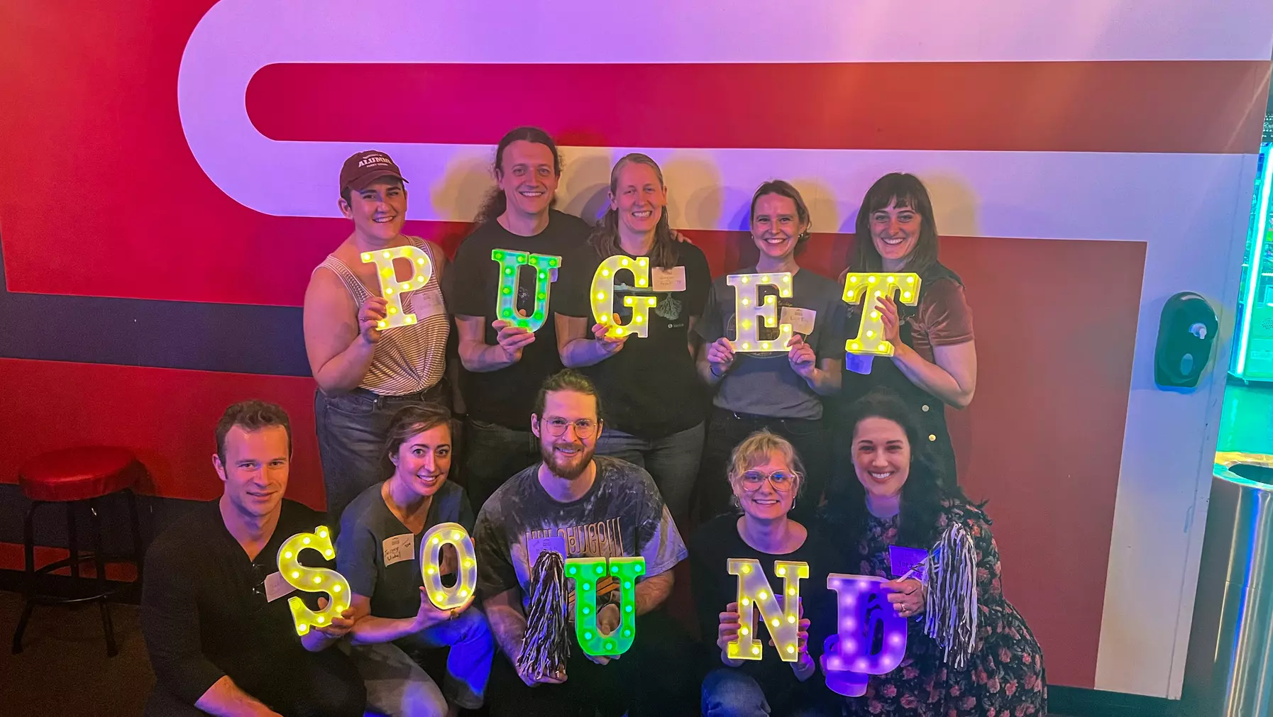 Group of Alumni Loggers holding painted letters that spell out "Puget Sound"