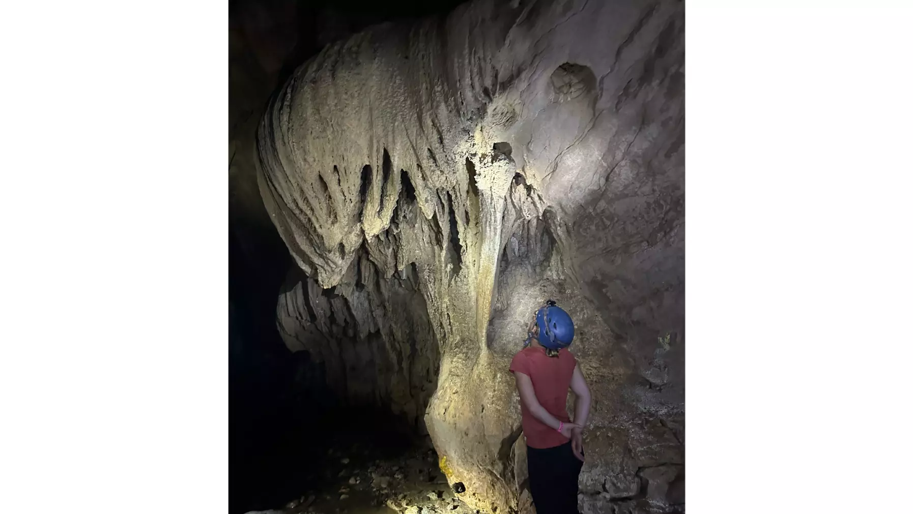 Student looks at a stalactite in a limestone cave in Costa Rica. Georney trip 2023.