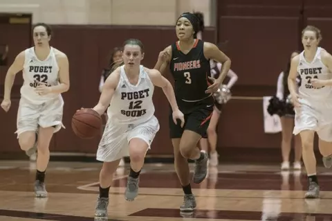 Puget Sound basketball players running across the court