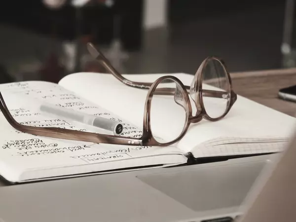 An open notebook with a pair of glasses placed on top