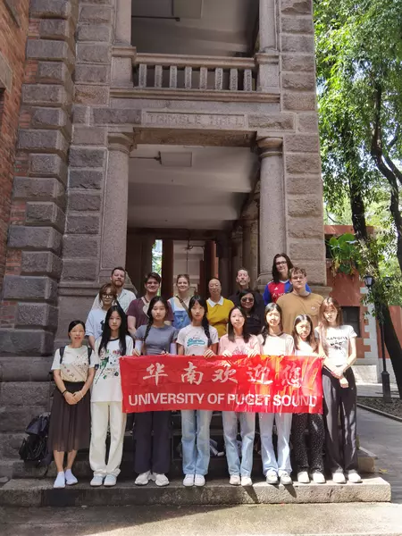 Students line up behind a red banner that says University of Puget Sound in English and Chinese letters