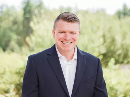 Tim Whittum wears a black blazer and white button-up shirt.